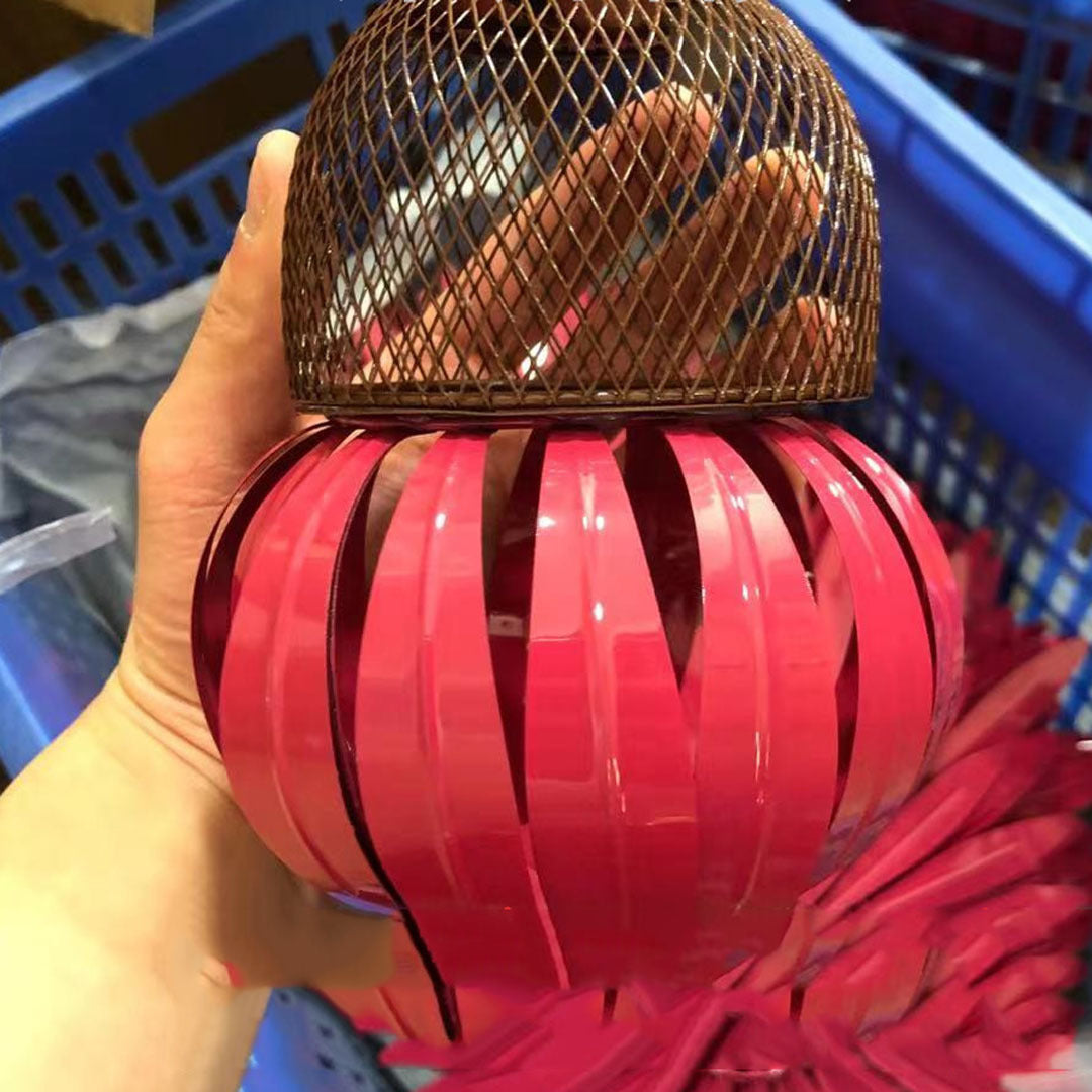 Red lantern with a mesh top held by a hand in a blue plastic basket.