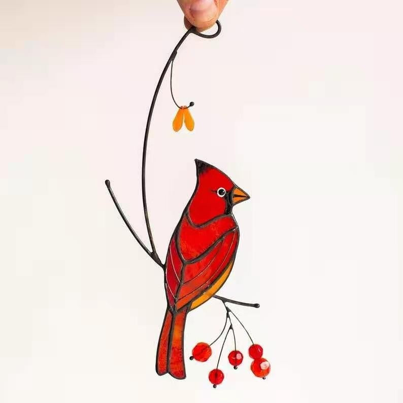 Stained glass cardinal bird ornament held by a hand on a white background