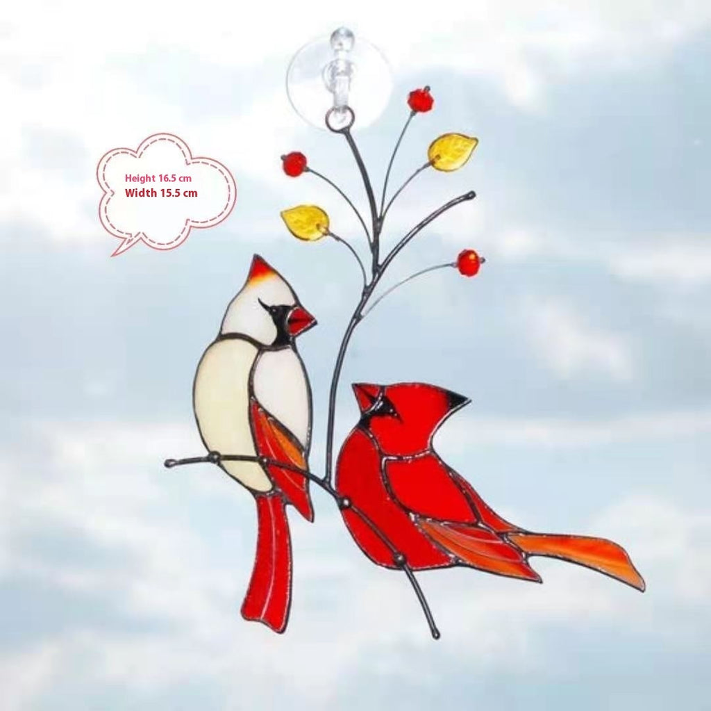Stained glass suncatcher of two cardinals on a branch with berries against a cloudy sky.